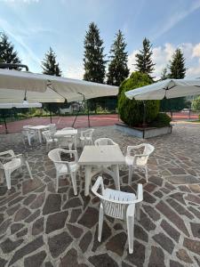a group of white tables and chairs with umbrellas at Dimora Ludovica in Selvino
