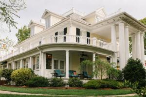 a white house with two blue chairs on the porch at The Edenton Collection – Granville Queen Inn in Edenton