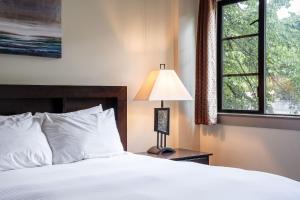 a bedroom with a bed and a lamp and a window at Selkirk Snug by Revelstoke Vacations in Revelstoke