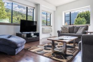 a living room with a couch and a tv at Selkirk Snug by Revelstoke Vacations in Revelstoke