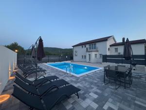 a patio with a pool and chairs and a table and a pool at Villa Imvelo Lovrec - Spacious Villa With Private Pool in Lovreć