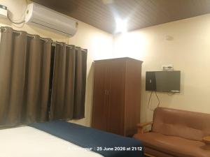 a bedroom with a bed and a tv and a couch at Vybhav Residency AC in Anantapur