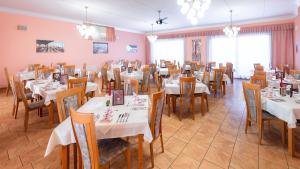 a dining room with white tables and wooden chairs at Strandhotel Orchidee in Sankt Kanzian