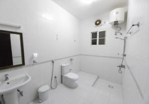 a white bathroom with a toilet and a sink at RED Bn Breek Villa in Salalah +26 photos