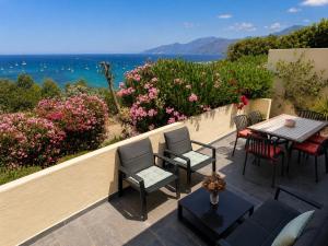 a patio with a table and chairs and the ocean at APPARTEMENT TERRASSE La Citadelle Appartements Saint Florent in Saint-Florent