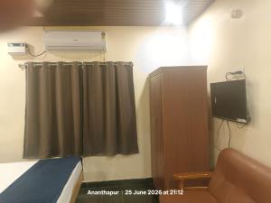 a room with a bed and a curtain and a television at Vybhav Residency AC in Anantapur