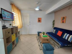 a living room with a blue couch and a tv at LE MANGO COSY ZEN proche de l'aéroport in Les Abymes