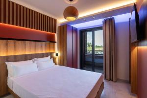 a bedroom with a large bed and a balcony at ZOI Girni - Seaside Hotel in Olympic Beach