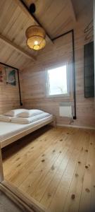 a bedroom with a bed in a wooden room at Szalona Gęś in Gąski