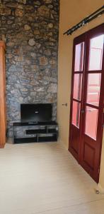 a door to a room with a tv and a stone wall at Thetis Stone Residence in Volissos