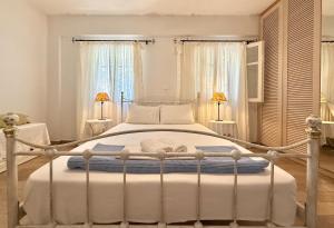 a bedroom with a white bed with two lamps at Villa Fenia in Aegiali