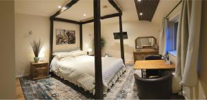 a bedroom with a four poster bed and a desk at Miltons Apartments and Rooms in Langford
