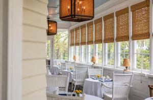a restaurant with white tables and chairs and windows at The Edenton Collection – Granville Queen Inn in Edenton