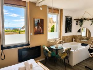 a bathroom with a tub and a table and chairs at L'instant d'évasion Vue mer in Lampaul-Plouarzel