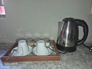 a tray with cups and plates and a tea kettle at Mams Cozy Guest house in Seshego