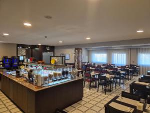 a restaurant with a bar and tables and chairs at Hotel Feira Pedra Bela in Santa Maria Da Feira