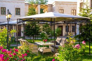 a gazebo with a table and chairs in a garden at Empire Cave Cappadocia in Göreme