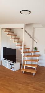 a living room with a staircase and a tv at Fewo Mandelsloh in Neustadt am Rübenberge