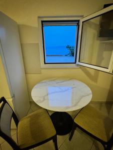 a white table and two chairs in a room with a window at Studio Apartment Rose in Selca