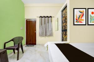 a bedroom with a bed and a chair and a door at HOTEL O GUMTHI in Māharjhari