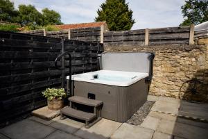a bath tub sitting next to a stone wall at Fuchsia Cottage - Accessible Comfort in Wilton