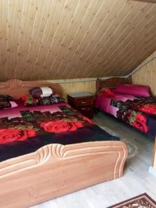 two beds in a room with a wooden ceiling at Апартаменти з гарним краєвидом in Yablunytsya