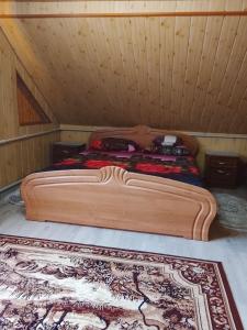 a wooden bed in a wooden room with a rug at Апартаменти з гарним краєвидом in Yablunytsya