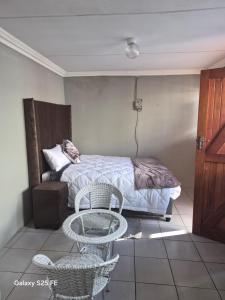 a bedroom with a bed and two chairs and a table at Mams Cozy Guest house in Seshego