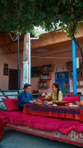 a man and woman sitting on a red bed at Gulzar Village Guesthouse in Dushanbe