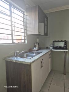a kitchen with a sink and a microwave at Mams Cozy Guest house in Seshego