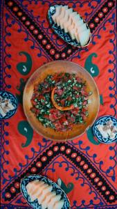 a table topped with a bowl of food on a table at Gulzar Village Guesthouse in Dushanbe