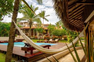 a hammock in front of a house with a pool at Samba Pousada in Jericoacoara