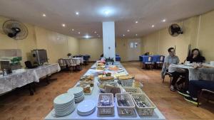 a long table filled with plates and bowls of food at Hotel Manoá Poa - Ambiente acolhedor e humanizado, seu refúgio estratégico no centro de Poa, próx a UFRGS, rodoviária e a Santa Casa in Porto Alegre
