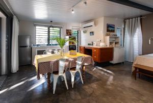a kitchen with a dining room table with chairs and a kitchen with a kitchen at Blue Zebra - Le Jardin d'Antoinette in Rivière Noire