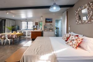 a bedroom with a large white bed and a kitchen at Blue Zebra - Le Jardin d'Antoinette in Rivière Noire