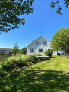 a white house on a hill with a yard at Öndólfsstaðir Farm B&B in Laugar