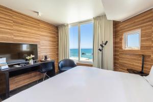a bedroom with a bed and a desk with a view of the ocean at Radisson Blu Acqua Hotel & Spa Concon in Concón