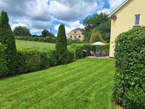 a yard with green grass and bushes and a house at 19 River Glen in Curracloe