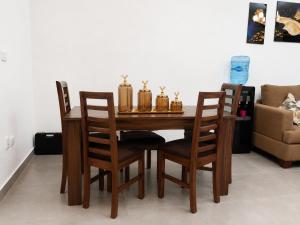 a wooden dining room table with four chairs and a couch at AMWAj in El Alamein +1 photo