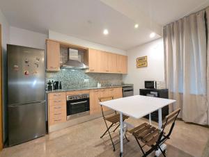 a kitchen with a table and a stainless steel refrigerator at Relax en Lloret con Gym y Piscina by Host&Joy in Lloret de Mar