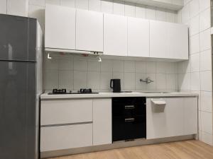 a kitchen with white cabinets and a refrigerator at 礁溪希沐湯泉民宿 2026年7月全新面貌登場 價格優惠中 in Jiaoxi