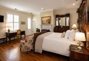 a bedroom with a large white bed and a desk at The Edenton Collection – Granville Queen Inn in Edenton