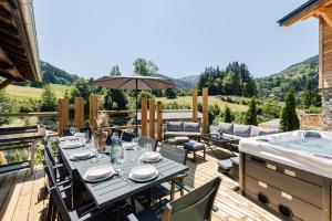 a patio with a table and a hot tub at Chalet des Granges 12 personnes Spa et cinéma in Morzine