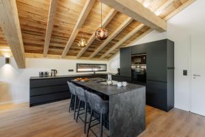 a kitchen with a black island with bar stools at Chalet des Granges 12 personnes Spa et cinéma in Morzine