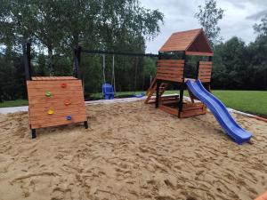 a playground with a slide and a playset in the sand at Tiny House Barujec in Brenna