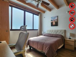 a bedroom with a bed and a chair and a window at Villa Alfonsina in Mexico City