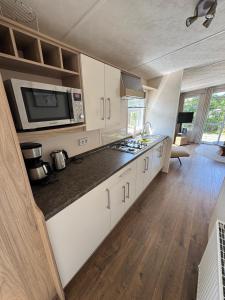 a kitchen with white cabinets and a microwave at Beach Chalet Sunny Dunes in Petten +7 photos