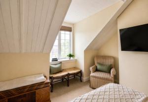 a attic bedroom with a bed and a chair at The Edenton Collection – Granville Queen Inn in Edenton