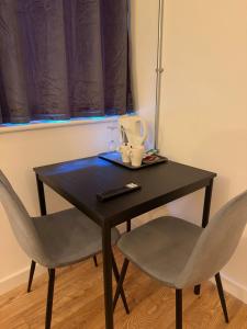 ein schwarzer Tisch mit zwei Stühlen und einer Fernbedienung in der Unterkunft The Nest Lite in Sheffield
