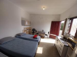 a bedroom with two beds and a kitchen with a window at Quarto superior Privativo in Itupeva